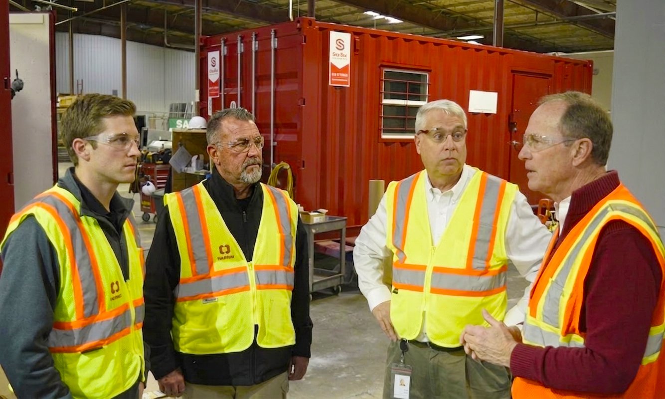 Personnel reviewing a modular blast-resistant building inside a manufacturing facility before deployment to an industrial site